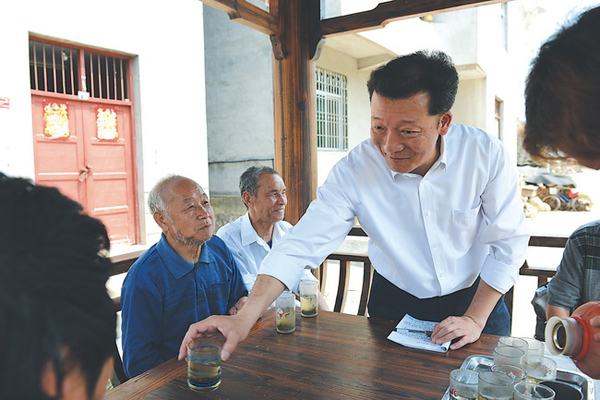 2014年4月18日，廖俊波（右一）在铁山东涧村调研，与村民座谈，给老人递上茶水。 徐庭盛 图